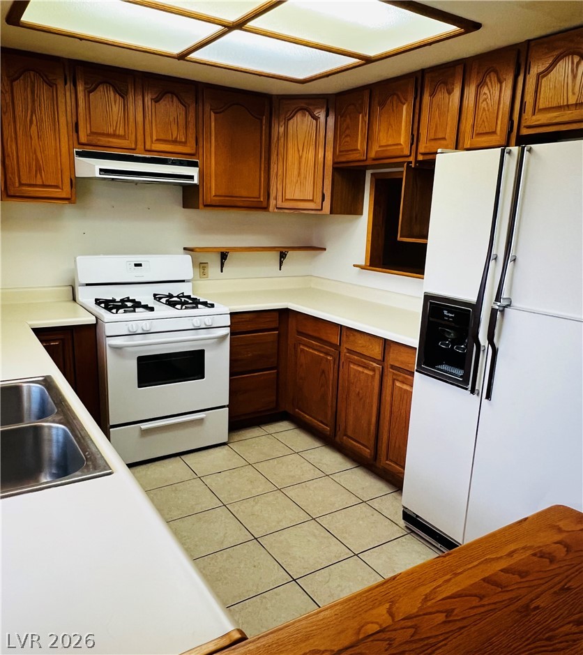 709 Ridgemount Drive Las Vegas, NV 89107 - Photo 2 of 40 Kitchen with white appliances, light countertops, light tile ceramic floors, and wood finish cabinetry