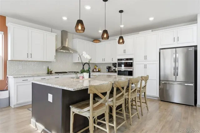 a kitchen with stainless steel appliances granite countertop a sink a stove a refrigerator cabinets and chairs