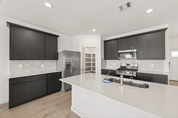 a kitchen with stainless steel appliances a stove a sink a refrigerator a counter top space and cabinets