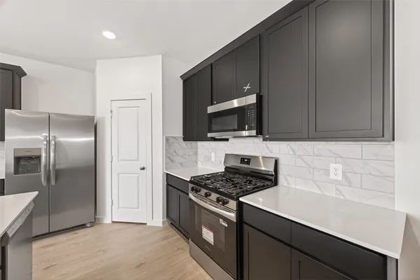 a kitchen with stainless steel appliances a refrigerator a sink a stove and cabinets