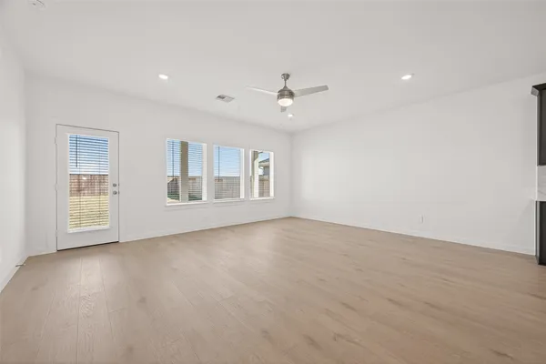 a view of an empty room with a window and wooden floor