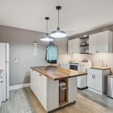 a kitchen with a stove a sink a refrigerator wooden floor cabinets and dining table