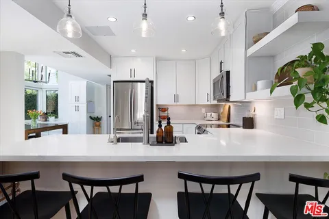 a kitchen with refrigerator and chairs