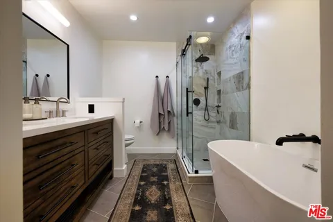 a bathroom with a double vanity sink a toilet a mirror and shower