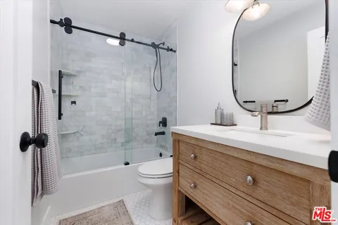 a bathroom with a granite countertop sink a toilet and shower