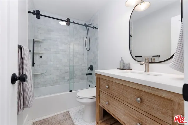a bathroom with a granite countertop sink a toilet and shower