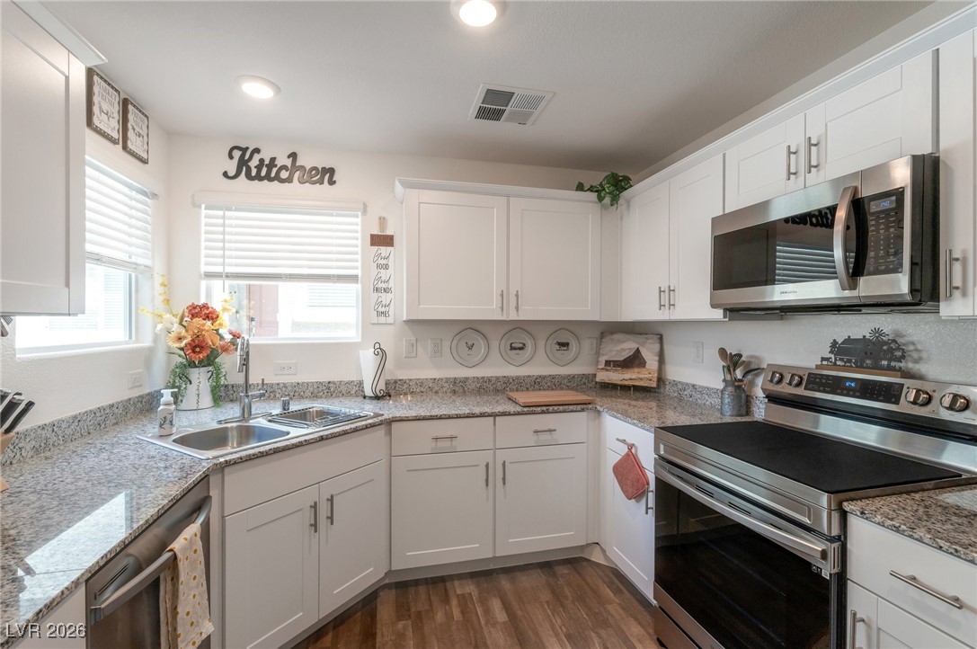 12348 Golden Wreath Road, Unit 1 Las Vegas, NV 89183 - Photo 3 of 37 Kitchen with appliances with stainless steel finishes, white cabinets, dark wood-type flooring, light stone counters, and recessed lighting