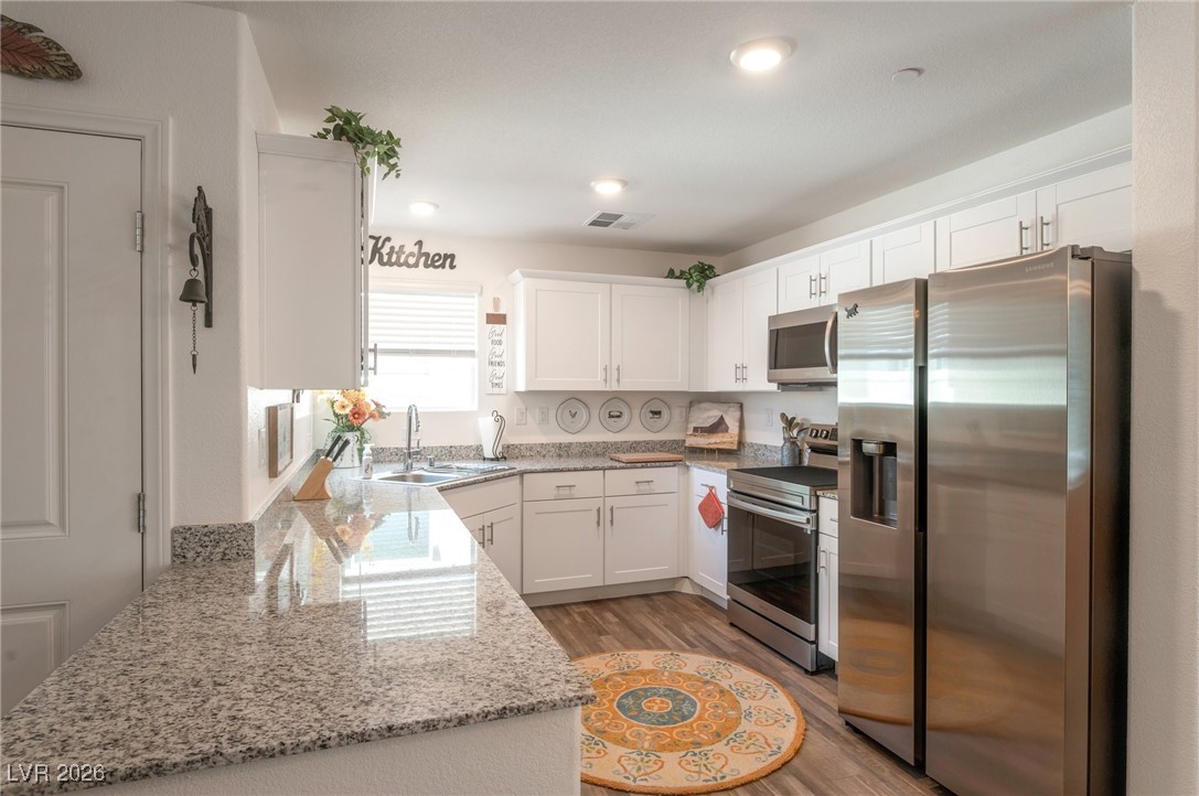 12348 Golden Wreath Road, Unit 1 Las Vegas, NV 89183 - Photo 4 of 37 Kitchen with stainless steel appliances, light stone counters, white cabinets, light wood-style flooring, and recessed lighting