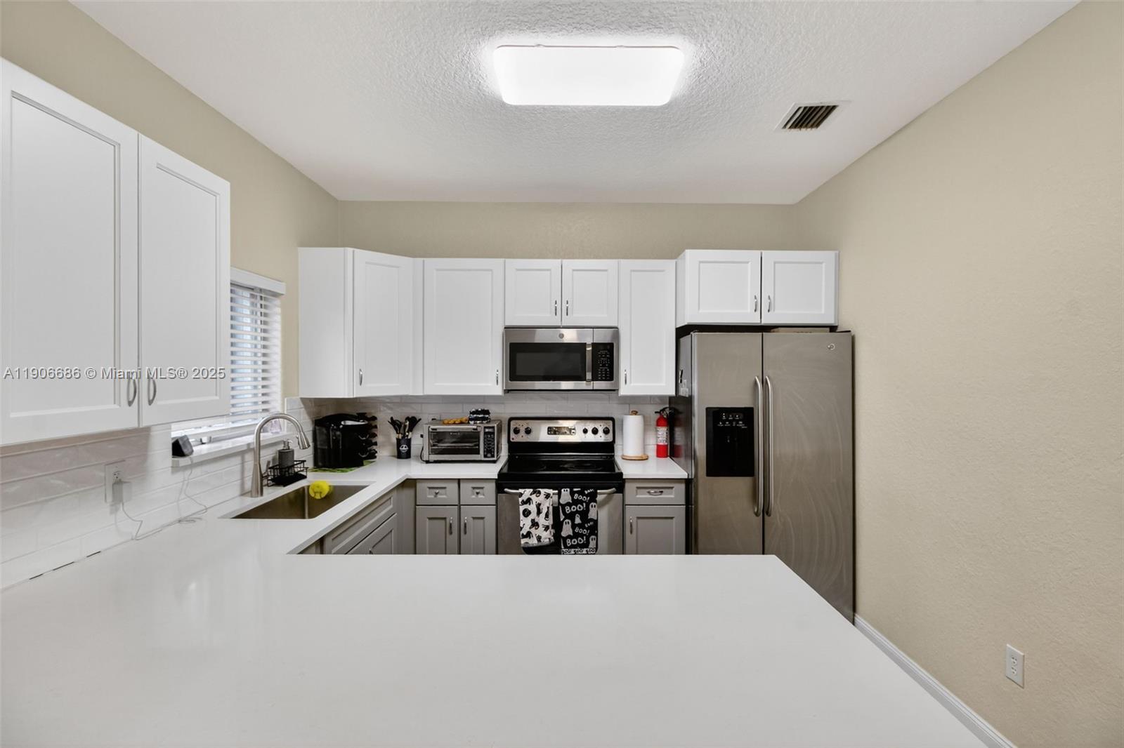 5302 Southwest 164th Place Miami, FL 33185 - Photo 13 of 43 a kitchen that has a refrigerator a stove top oven a sink a counter space and cabinets