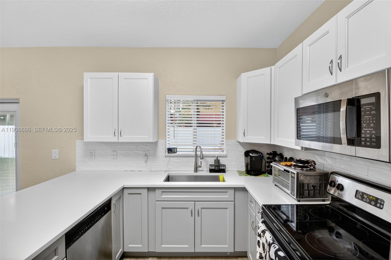 5302 Southwest 164th Place Miami, FL 33185 - Photo 14 of 43 a kitchen with a sink stove top oven and cabinets