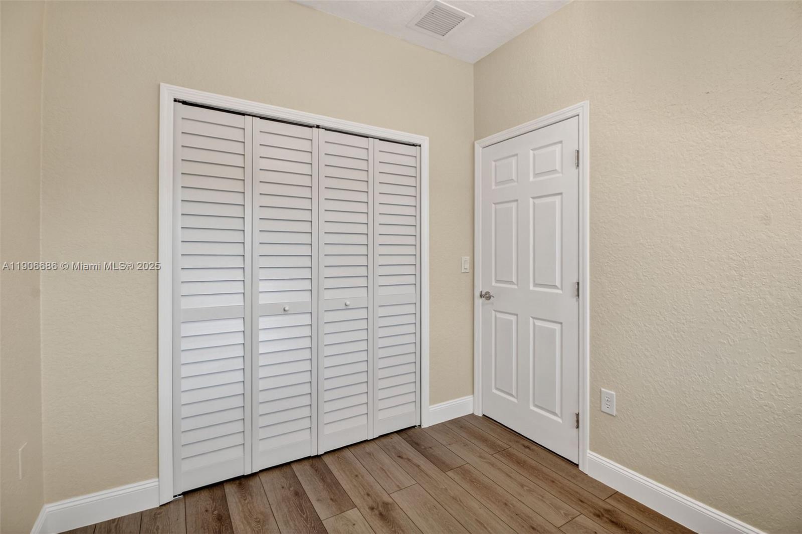 5302 Southwest 164th Place Miami, FL 33185 - Photo 19 of 43 an empty room with wooden floor and white walls