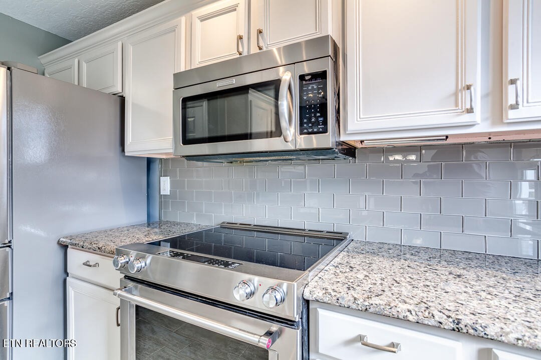 1296 Emerald Forest Lane Powell, TN 37849 - Photo 18 of 43 a kitchen with granite countertop white cabinets stainless steel appliances and a counter space
