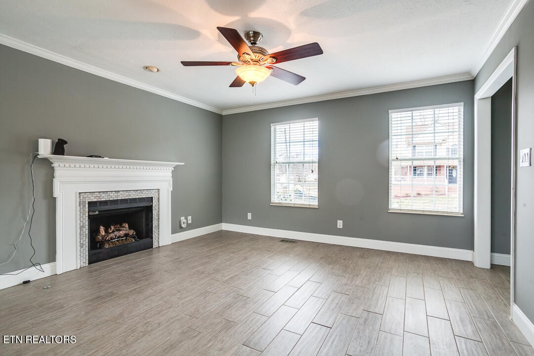 1296 Emerald Forest Lane Powell, TN 37849 - Photo 6 of 43 an empty room with windows a fireplace a ceiling fan and wooden floor