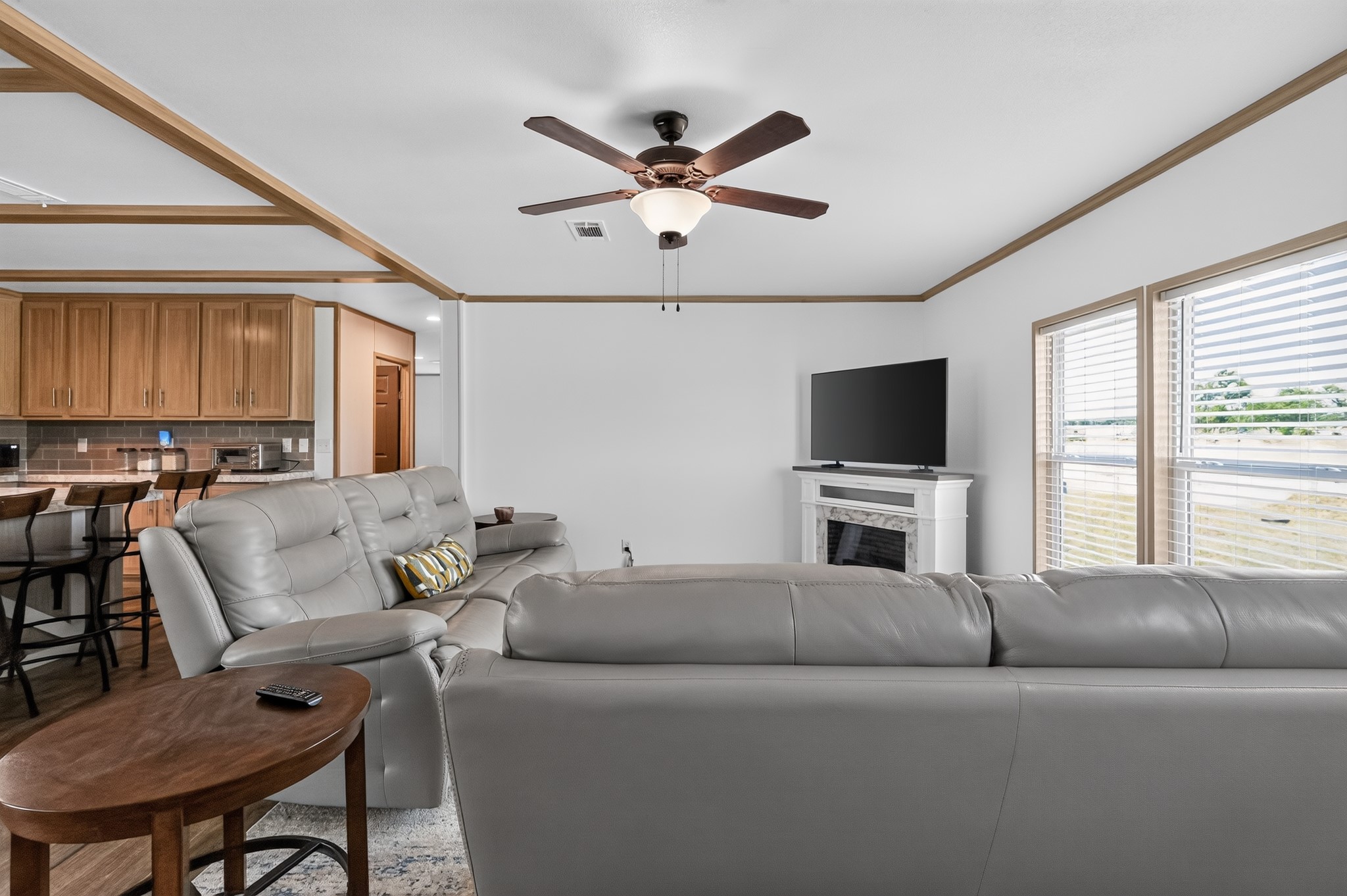 1134 Switchgrass Road Salado, TX 76571 - Photo 12 of 28 A comfortable living area features a decorative fireplace, large windows, and an adjacent kitchen bar.