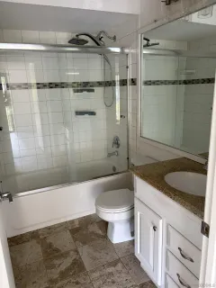 a bathroom with a granite countertop sink a toilet and shower