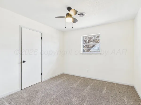 an empty room with closet and a ceiling fan
