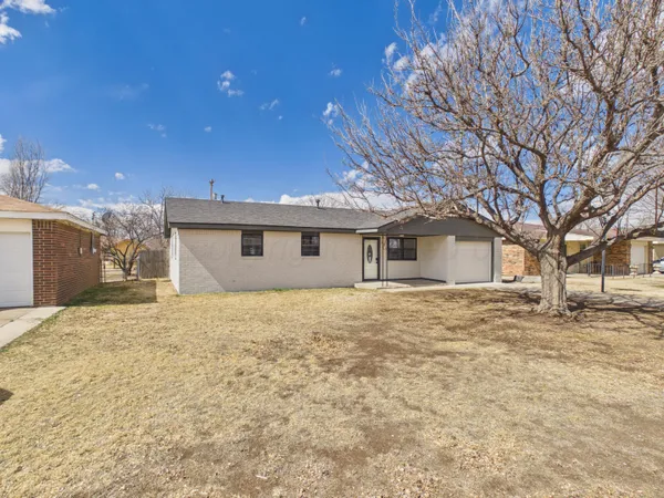 a view of a yard in front of a house with a large tree