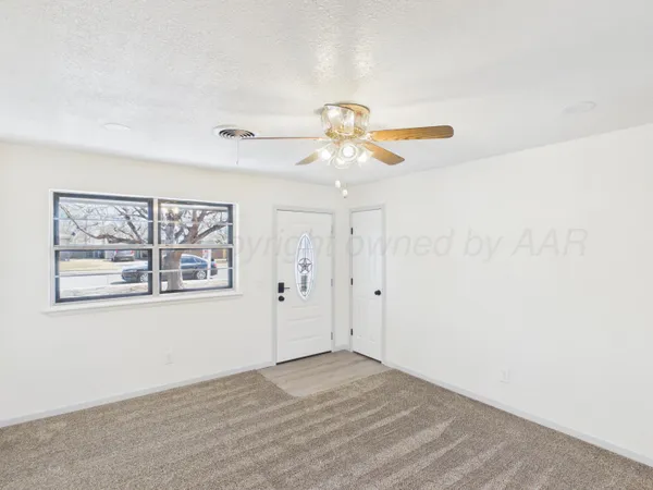 an empty room with windows and fan