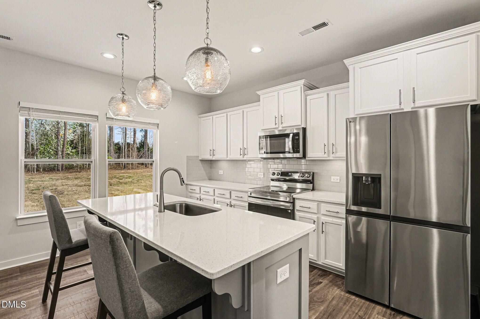 51 East Dentaires Way Willow Spring, NC 27592 - Photo 12 of 39 a kitchen with stainless steel appliances granite countertop a refrigerator a sink dishwasher a stove top oven a refrigerator with island and chairs