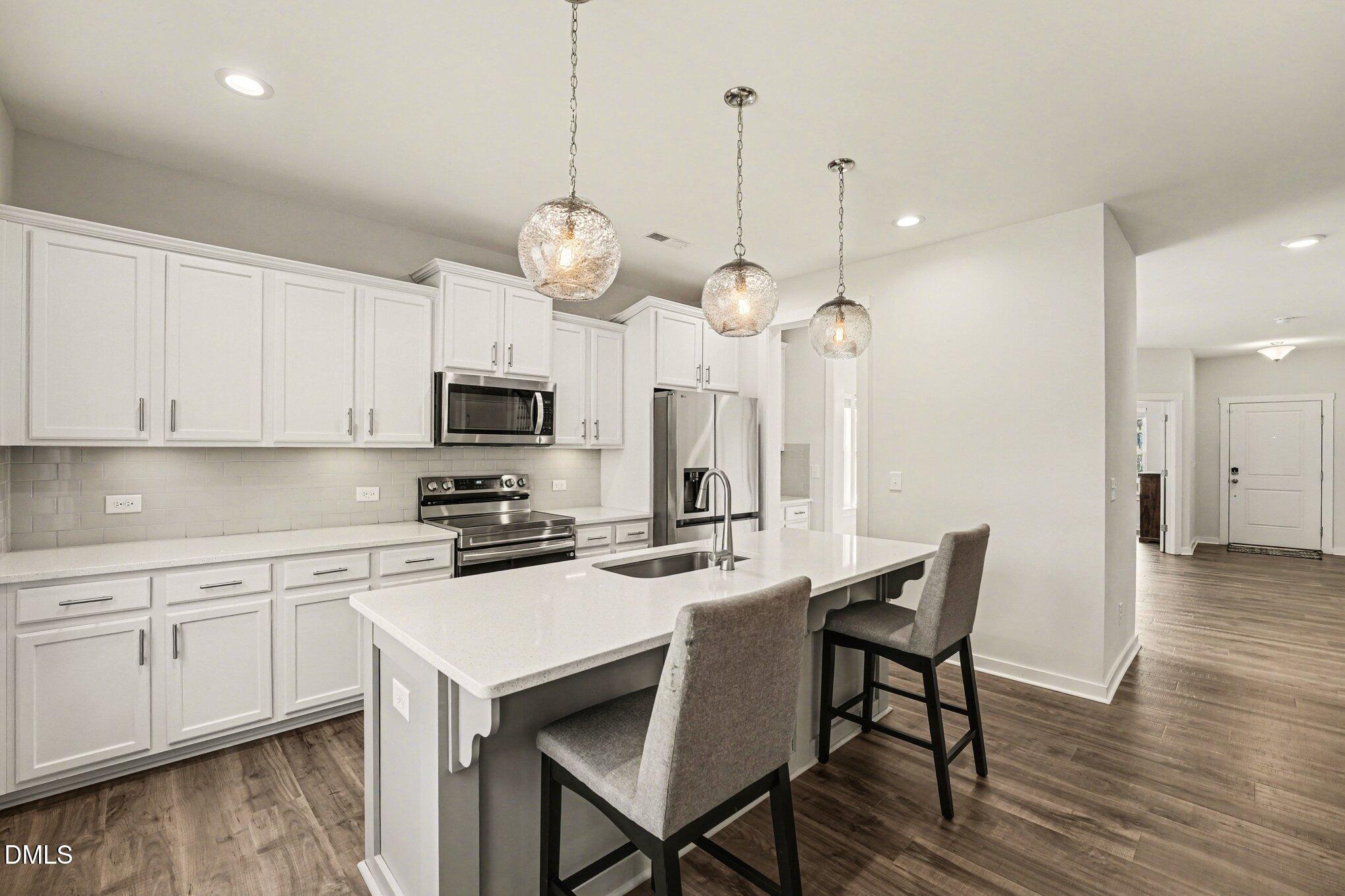 51 East Dentaires Way Willow Spring, NC 27592 - Photo 15 of 39 a kitchen with stainless steel appliances a dining table chairs and white cabinets