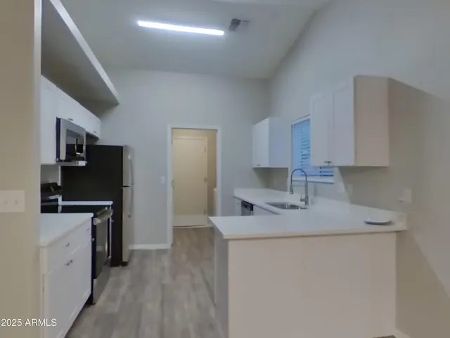 a view of an empty room with wooden floor and a bathroom