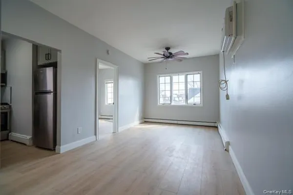 a view of an empty room with a window and wooden floor