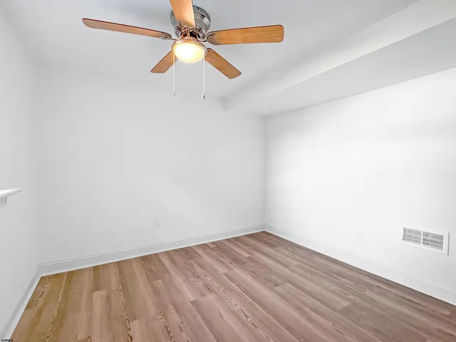 an empty room with a ceiling fan and wooden floor