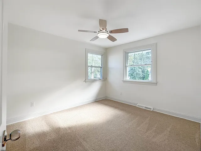an empty room with windows and fan