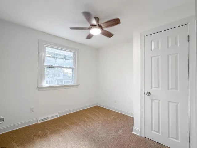 an empty room with a window and a ceiling fan