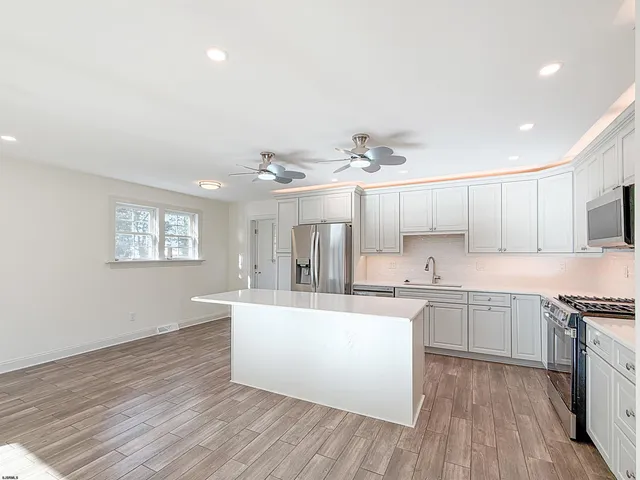 a large kitchen with cabinets wooden floor and stainless steel appliances