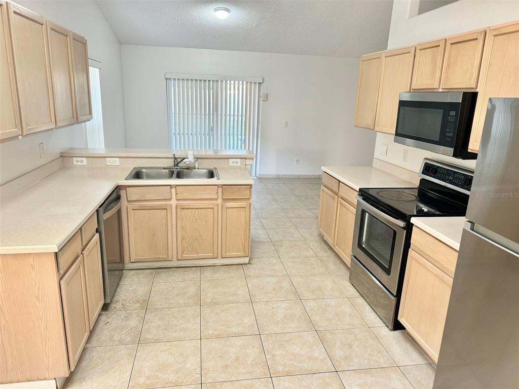 147 South Roma Way Kissimmee, FL 34746 - Photo 2 of 11 a kitchen with stainless steel appliances a stove sink and microwave