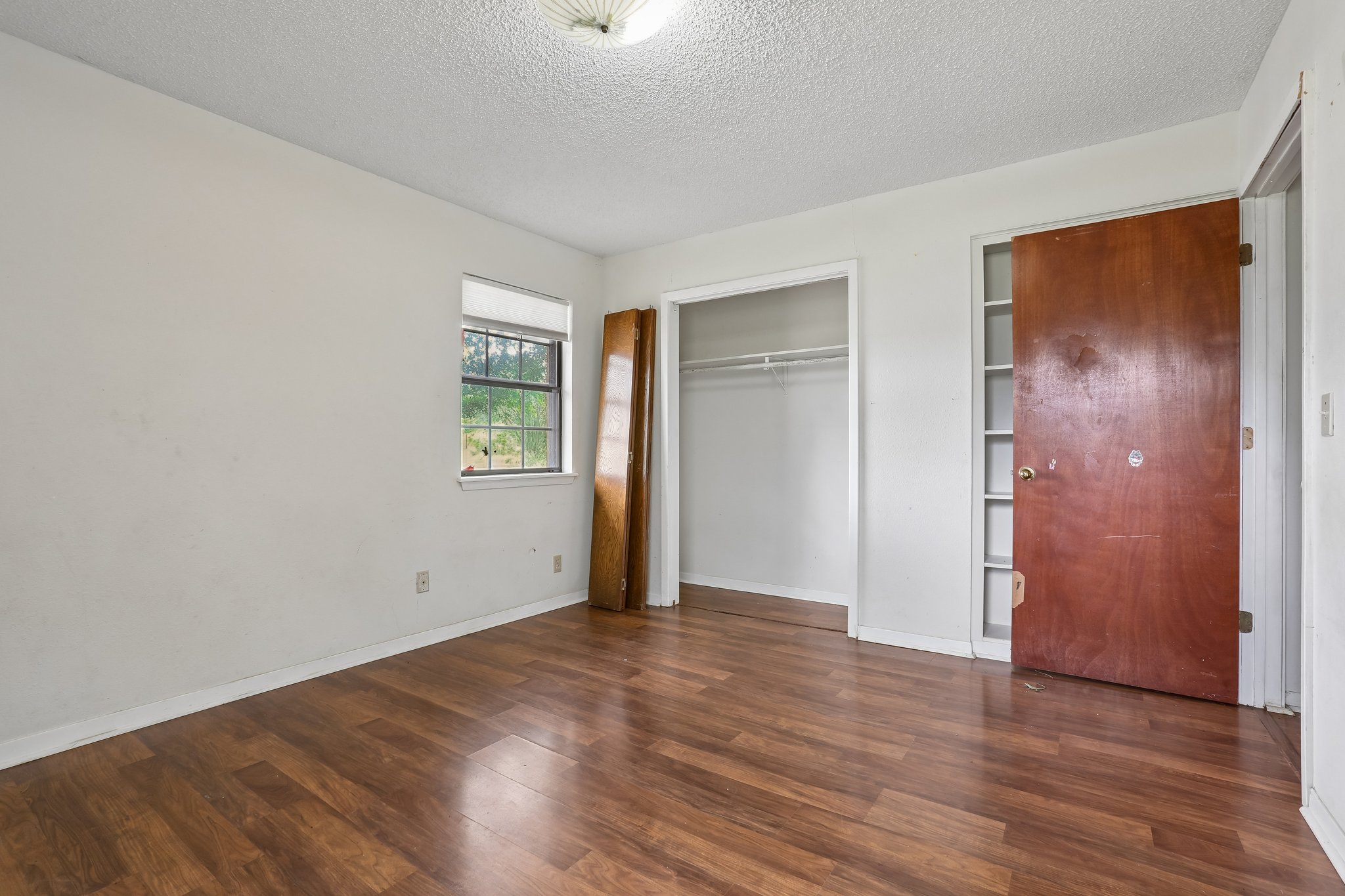 406 Monkey Road Elgin, TX 78621 - Photo 24 of 39 Bedroom featuring wood-finish flooring, a window with natural light, and two built-in storage areas
