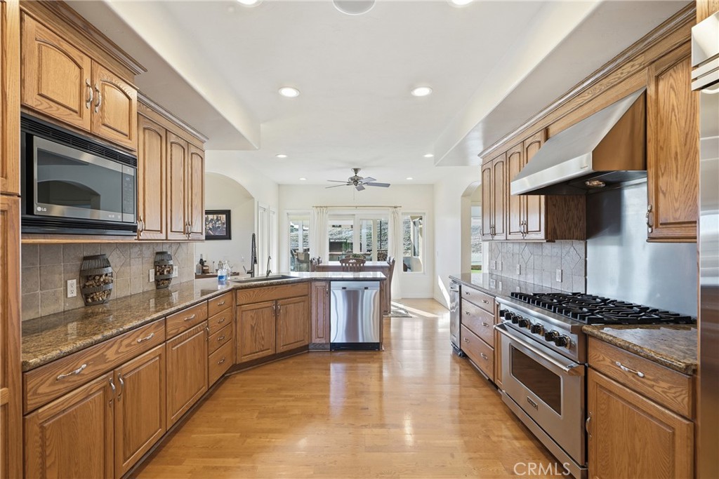 220 Cook Court Templeton, CA 93465 - Photo 11 of 45 a kitchen with stainless steel appliances kitchen island granite countertop a stove top oven a sink dishwasher a dining table and chairs with wooden floor