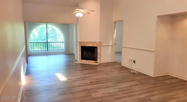 an empty room with wooden floor fireplace and windows