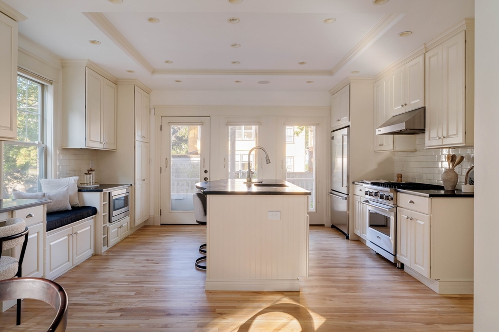 54 Orchard Street, Unit 1 Boston, MA 02130 - Photo 10 of 36 a kitchen with stainless steel appliances granite countertop a stove top oven a sink a refrigerator white cabinets and wooden floor