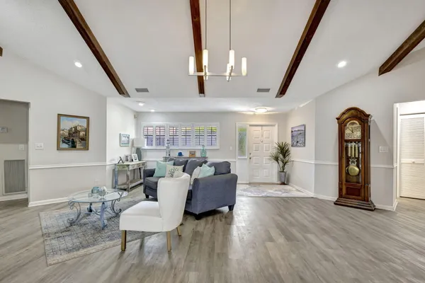 a living room with furniture a potted plant and a kitchen view