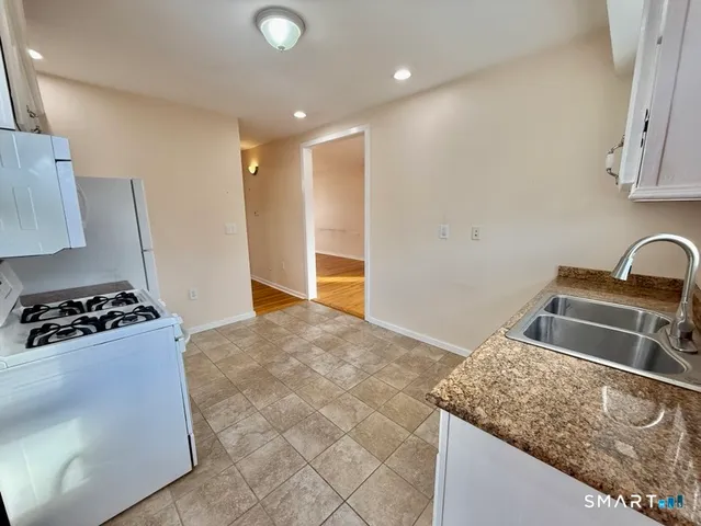a kitchen with granite countertop a refrigerator and a stove top oven