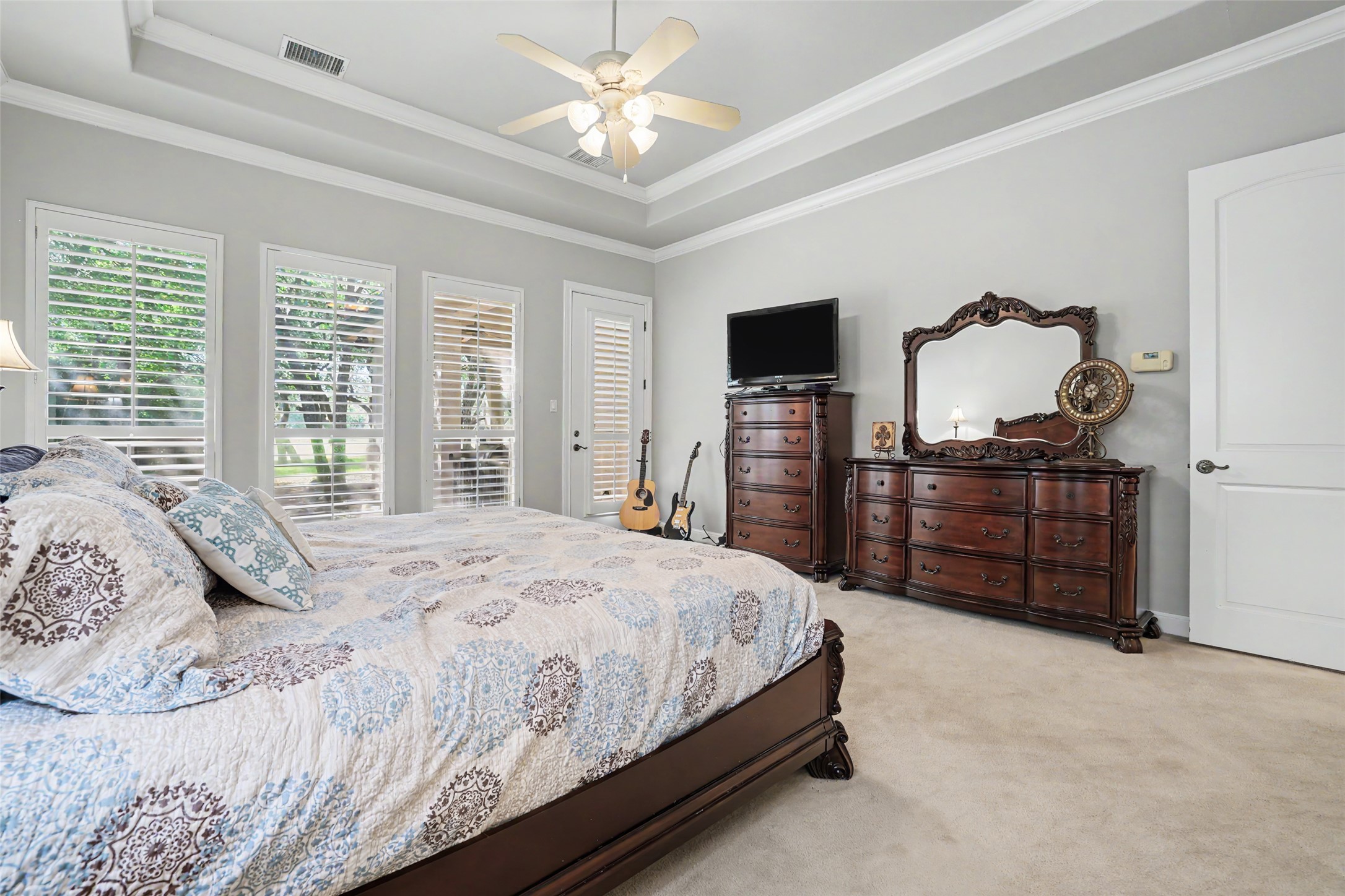 33 Meadows End Georgetown, TX 78628 - Photo 19 of 40 Elegant tray ceilings crown this well-lit bedroom, featuring a private exterior door for seamless outdoor access.