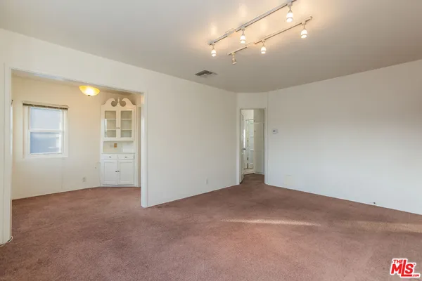 a view of an empty room with cabinet and mirrors