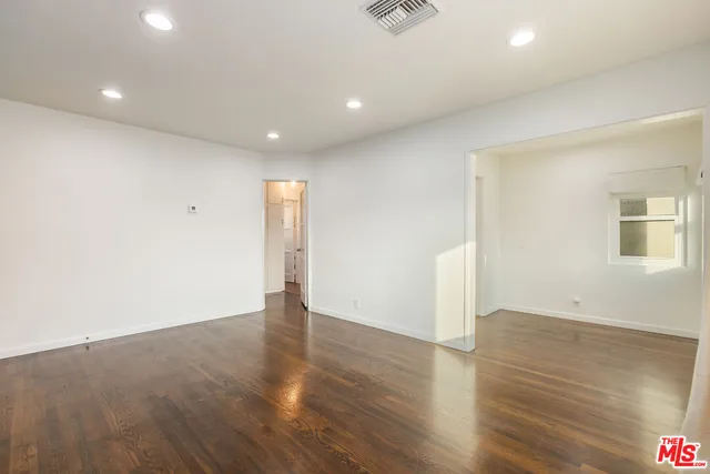 an empty room with wooden floor and fan