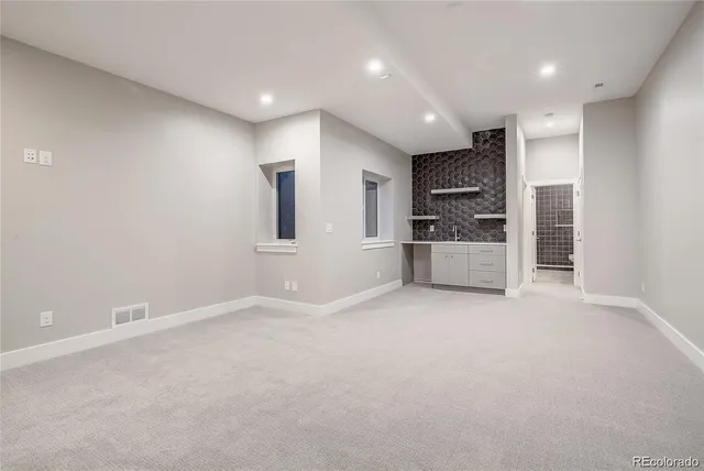 an empty room with kitchen and windows