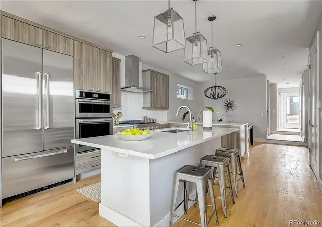 a kitchen with stainless steel appliances a dining table chairs refrigerator and microwave