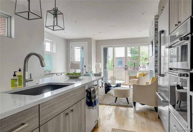 a kitchen with a sink a counter appliances and living room view