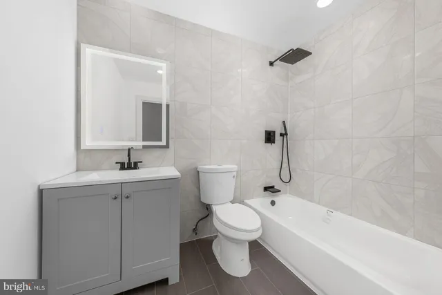 a bathroom with a toilet sink vanity tub and mirror