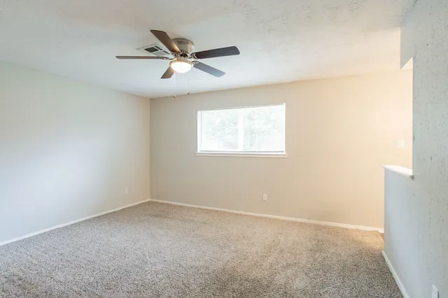 an empty room with a window and a fan