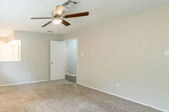 an empty room with a ceiling fan and window