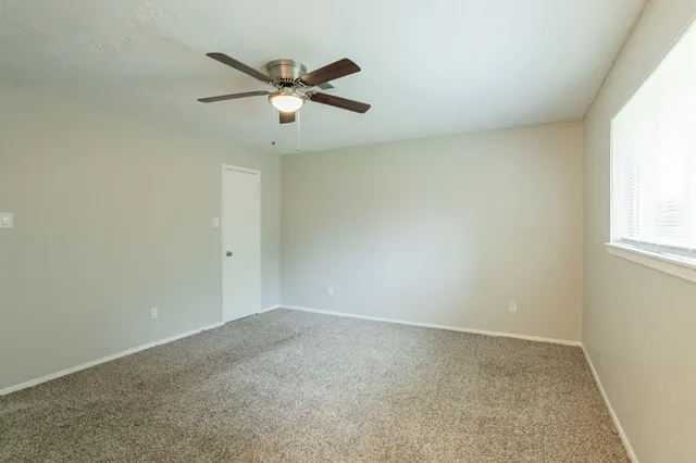an empty room with a window and a fan