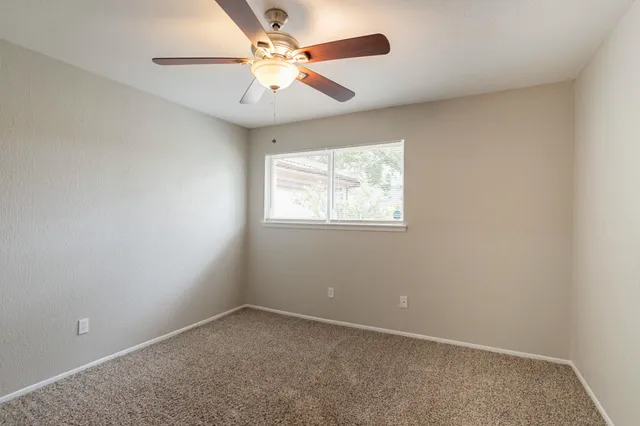an empty room with a window and a fan