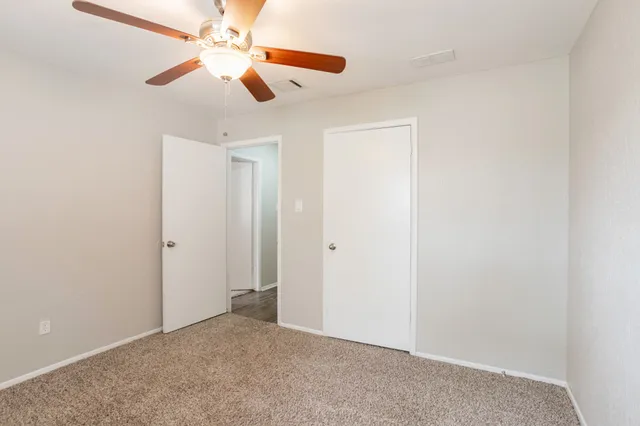 an empty room with closet and a chandelier fan