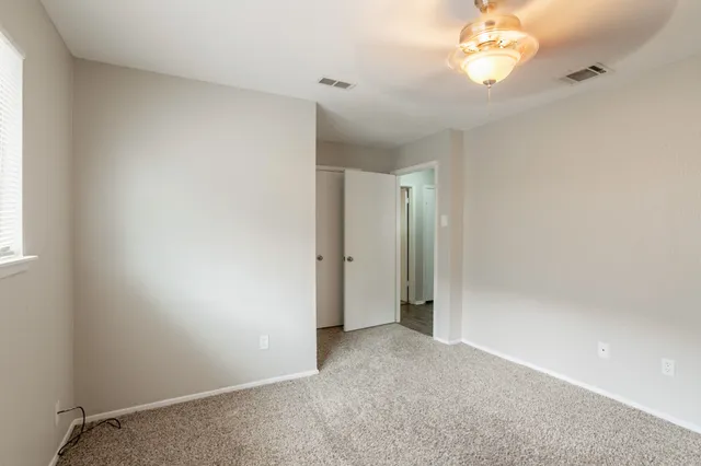 an empty room with a chandelier fan and wooden floor